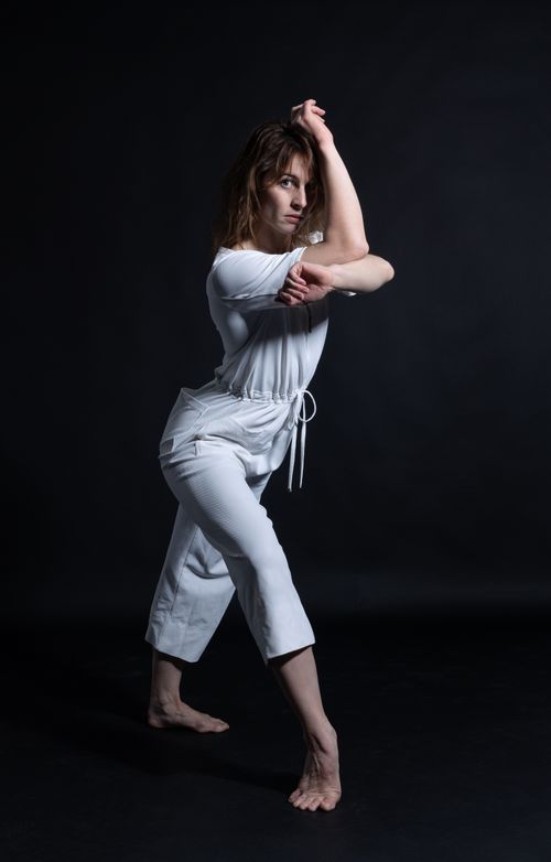 Free Elegant woman performing dance pose in studio with dramatic lighting. Stock Photo