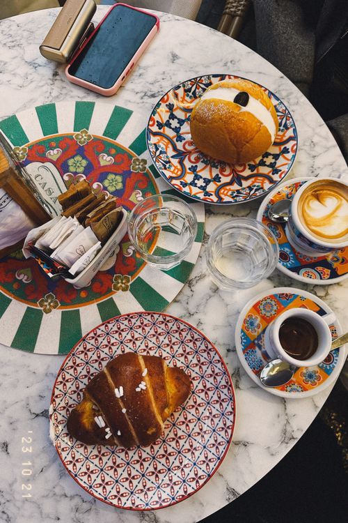 Free A vibrant breakfast setting in Napoli featuring coffee, croissants, and colorful ceramic plates. Stock Photo