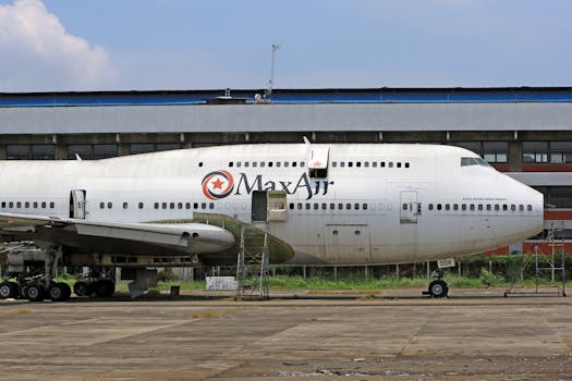 Max Air Boeing 747 parked on a runway with hangar backdrop.