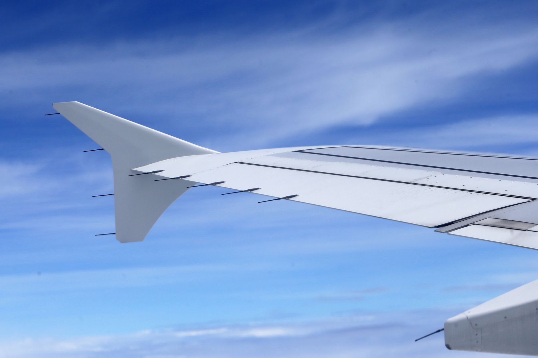 View of an airplane wing against a vibrant blue sky, capturing the essence of air travel.