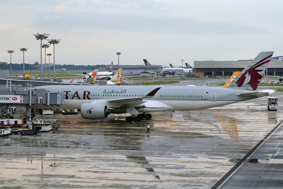 Qatar Airways airplane parked at international airport terminal during daytime.