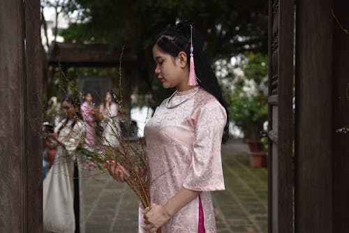 A woman in a pink dress holding flowers