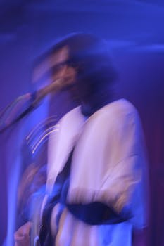 Blurred image of a musician passionately performing on stage with blue lighting.