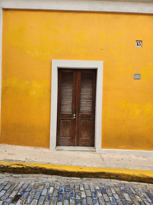 Free Vibrant yellow building facade with shuttered wooden door in historic San Juan, Puerto Rico. Stock Photo