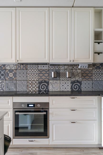Elegant kitchen with white cabinets complemented by an intricate patterned mosaic tile backsplash creating visual texture - photo by Alex Tyson