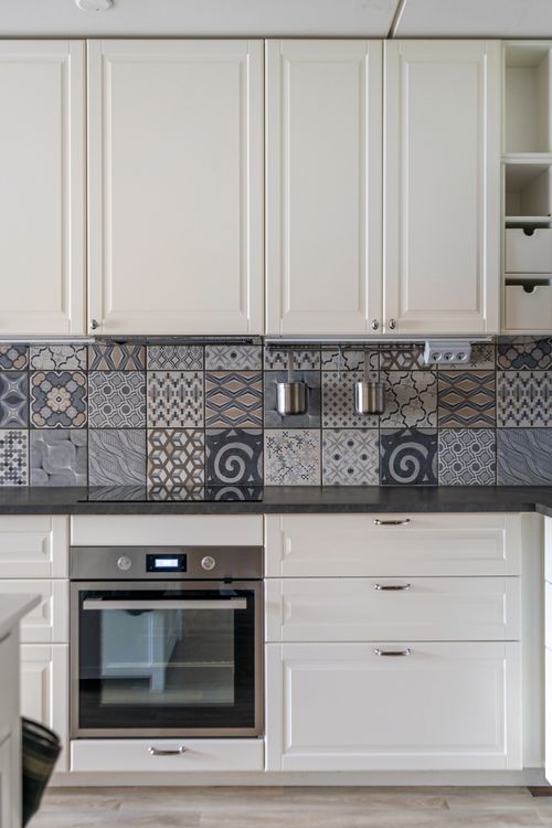 Free Elegant kitchen design featuring white cabinets and a patterned mosaic tile backsplash. Stock Photo
