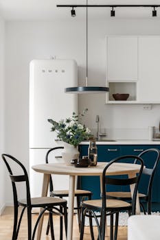 Elegant minimalist kitchen scene with blue cabinets and contemporary furniture.