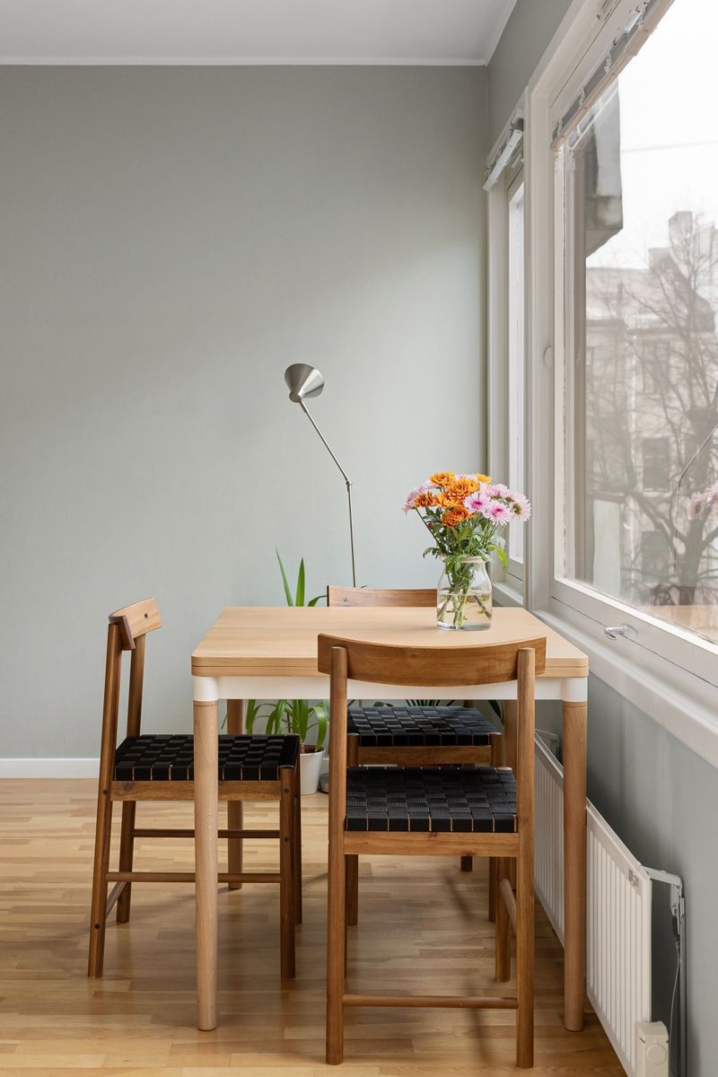 Wooden dining table with chairs by a bright apartment window