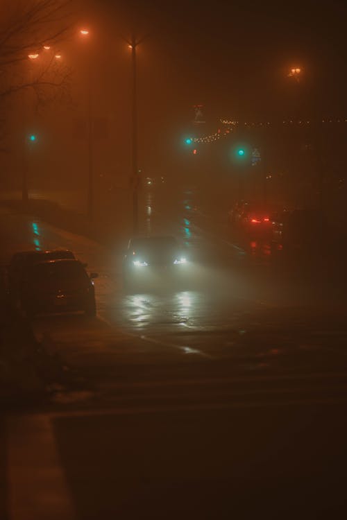 A foggy street with cars driving through it