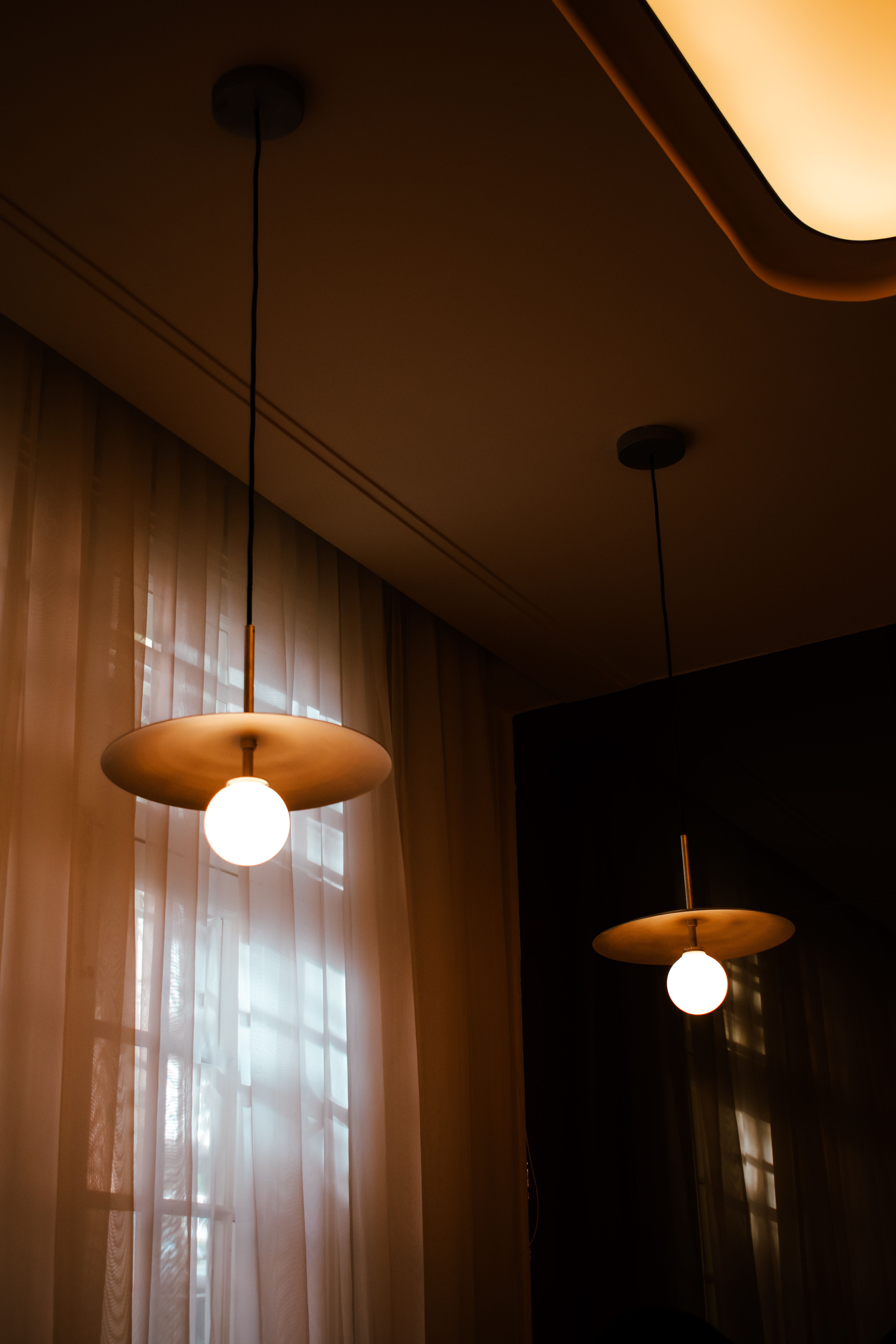 Stylish interior featuring modern hanging pendant lights against sheer curtains.