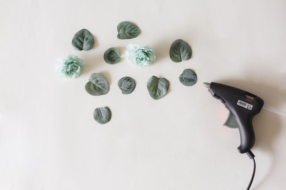 Arrangement of artificial flowers and leaves with a glue gun, perfect for DIY crafts.