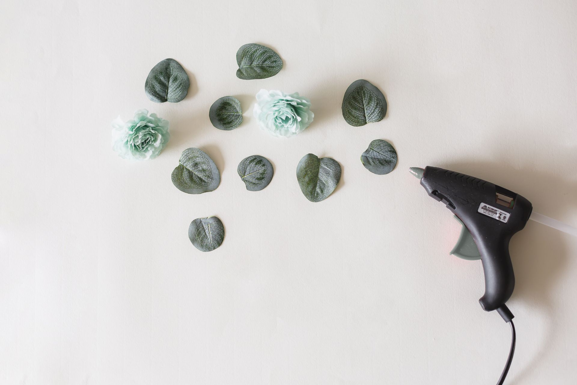 Arrangement of artificial flowers and leaves with a glue gun, perfect for DIY crafts.