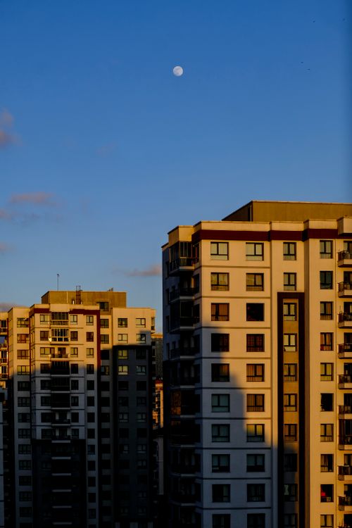 Free High-rise apartment buildings in Istanbul at sunset with the moon visible in the clear sky. Stock Photo