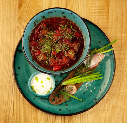 A bowl of soup with meat and vegetables on a plate