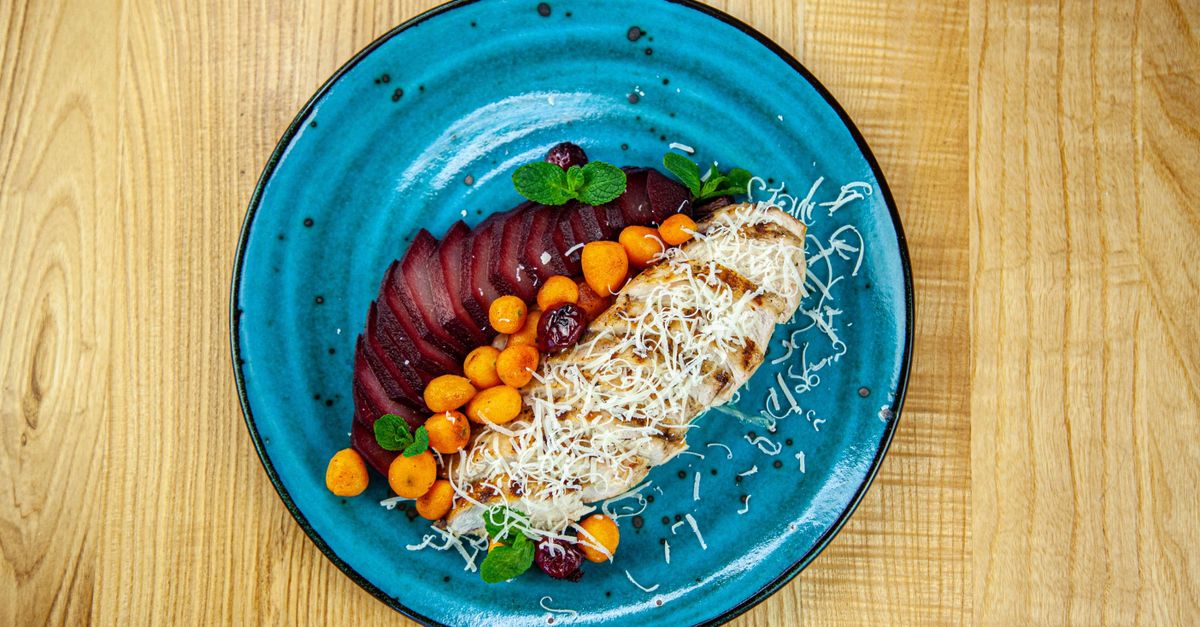 Grilled chicken with fruit and vegetables on a blue plate