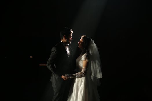 A bride and groom share an intimate dance, illuminated by a spotlight, creating a romantic atmosphere.