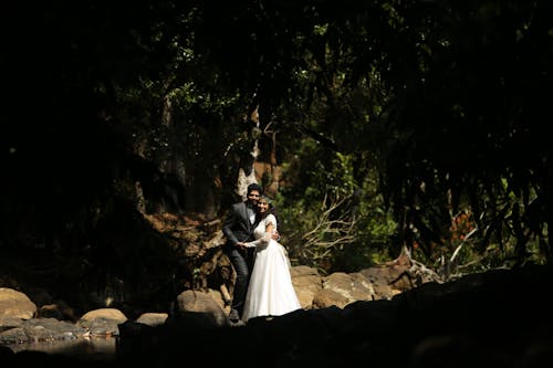 Newlyweds Hugging under Trees in Forest