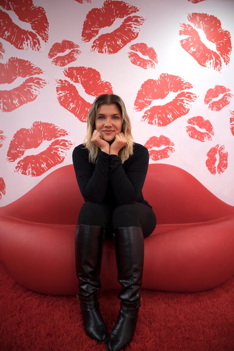 Woman Sitting On Red Lips Sofa Inside Room