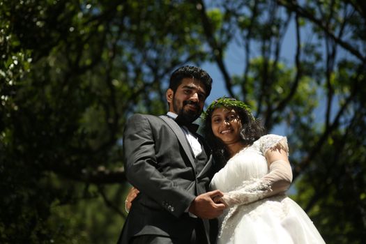 A joyful outdoor wedding portrait of a smiling couple in wedding attire, surrounded by nature.