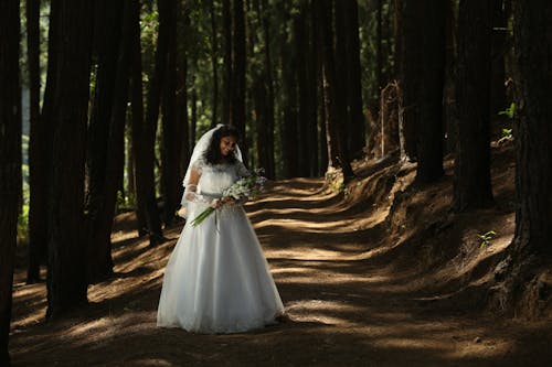 Brunette Bride in Wedding Dress Posing in Forest