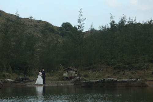 Newlyweds Standing by Lake in Forest