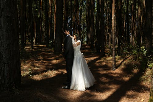 A bride and groom standing in the woods