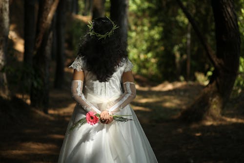 Brunette Woman Standing in Wedding Dress in Forest
