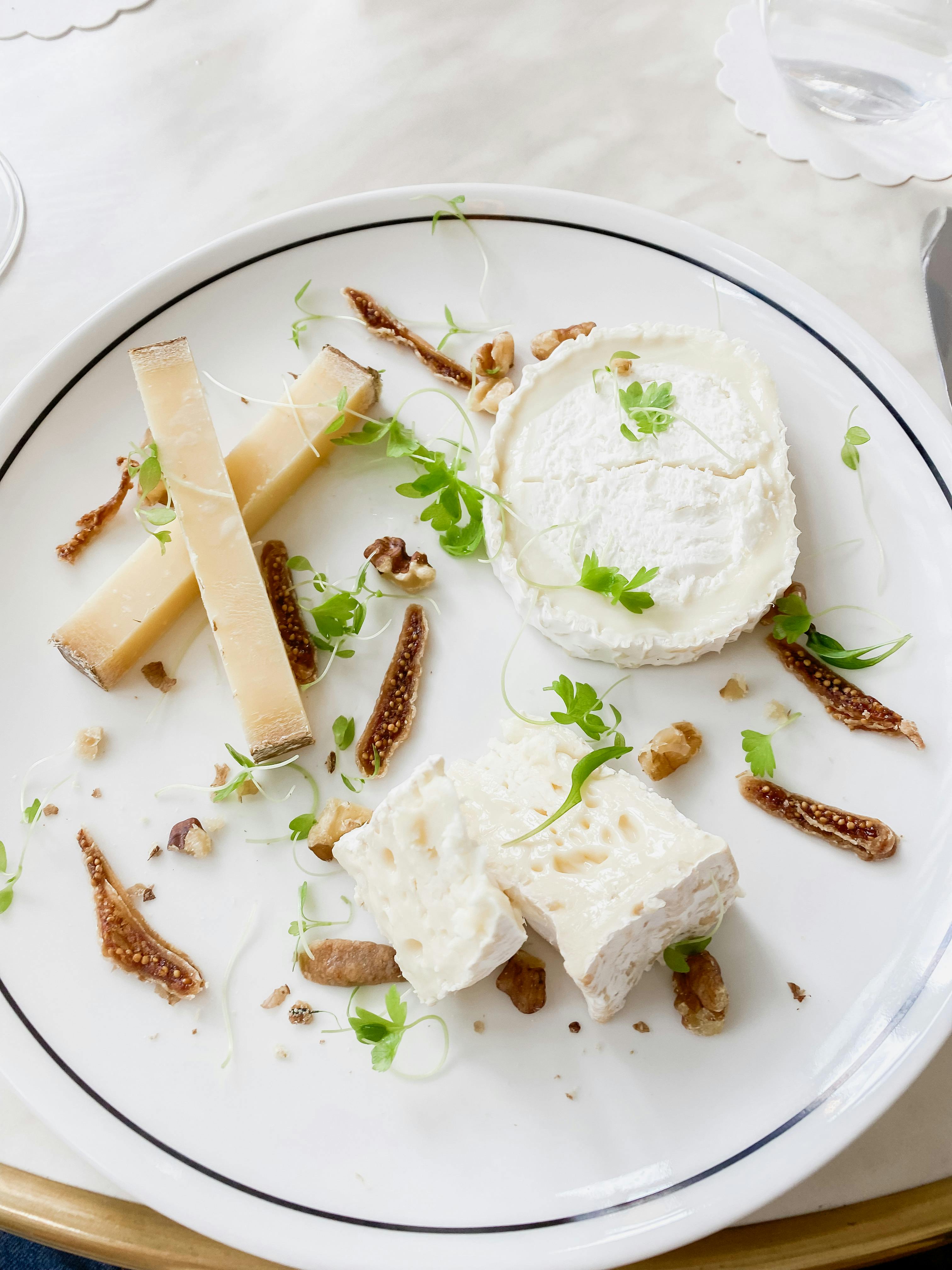 Elegant platter showcasing gourmet cheeses, nuts, and fresh greens on a white plate.