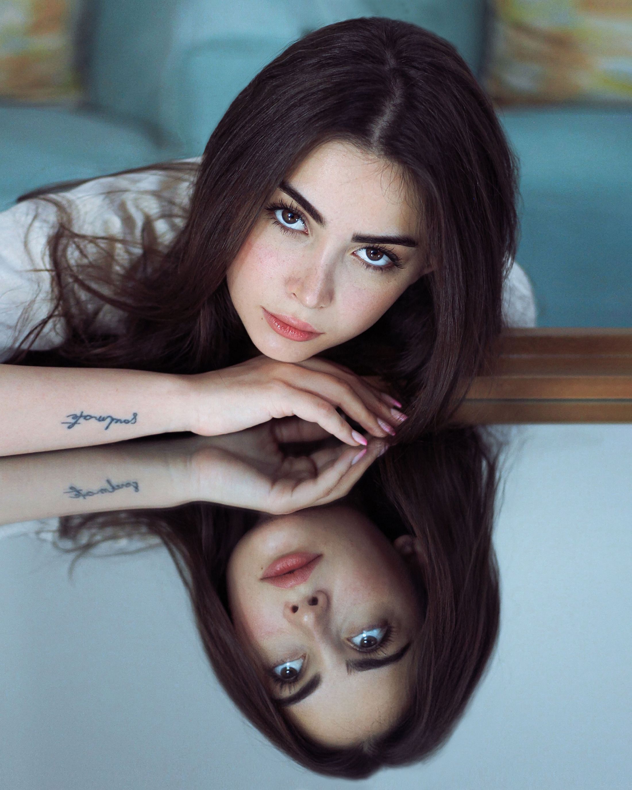 A captivating portrait of a woman with a tattoo, reflected in a mirror, capturing a serene and artistic mood.