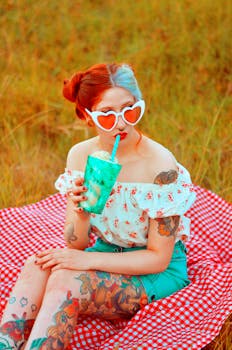 一位有纹身的时尚女性在夏日野餐时喝着饮料