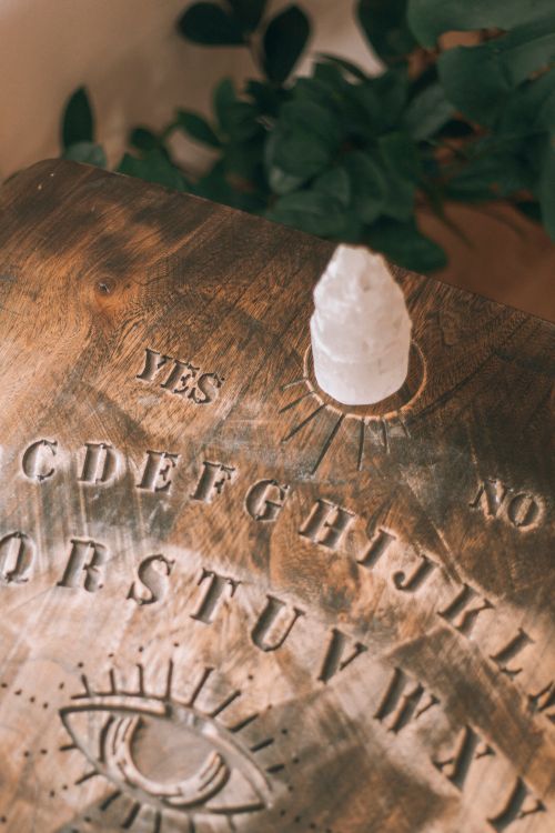 Free A close-up of a carved wooden Ouija board with a crystal pointer, emphasizing spirituality and mysticism. Stock Photo