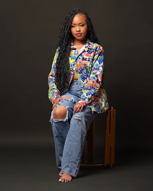 Woman Sitting in Torn Jeans and Colorful Shirt