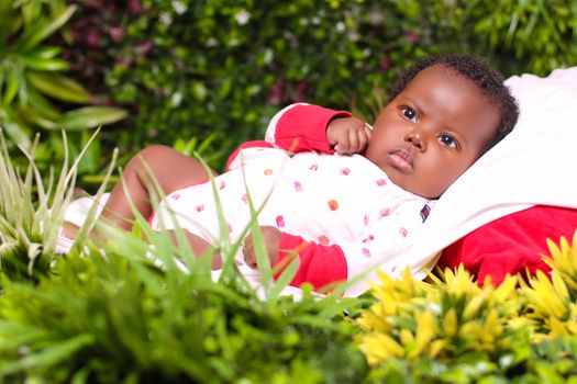 Charming baby lying on a blanket in a lush garden setting, perfect for family and childhood themes.