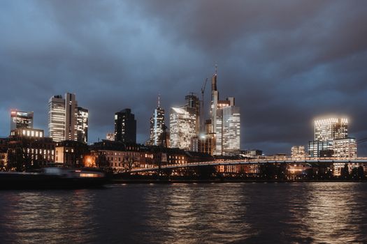 Beautiful view of Frankfurt's illuminated skyline at dusk, reflecting on the River Main.