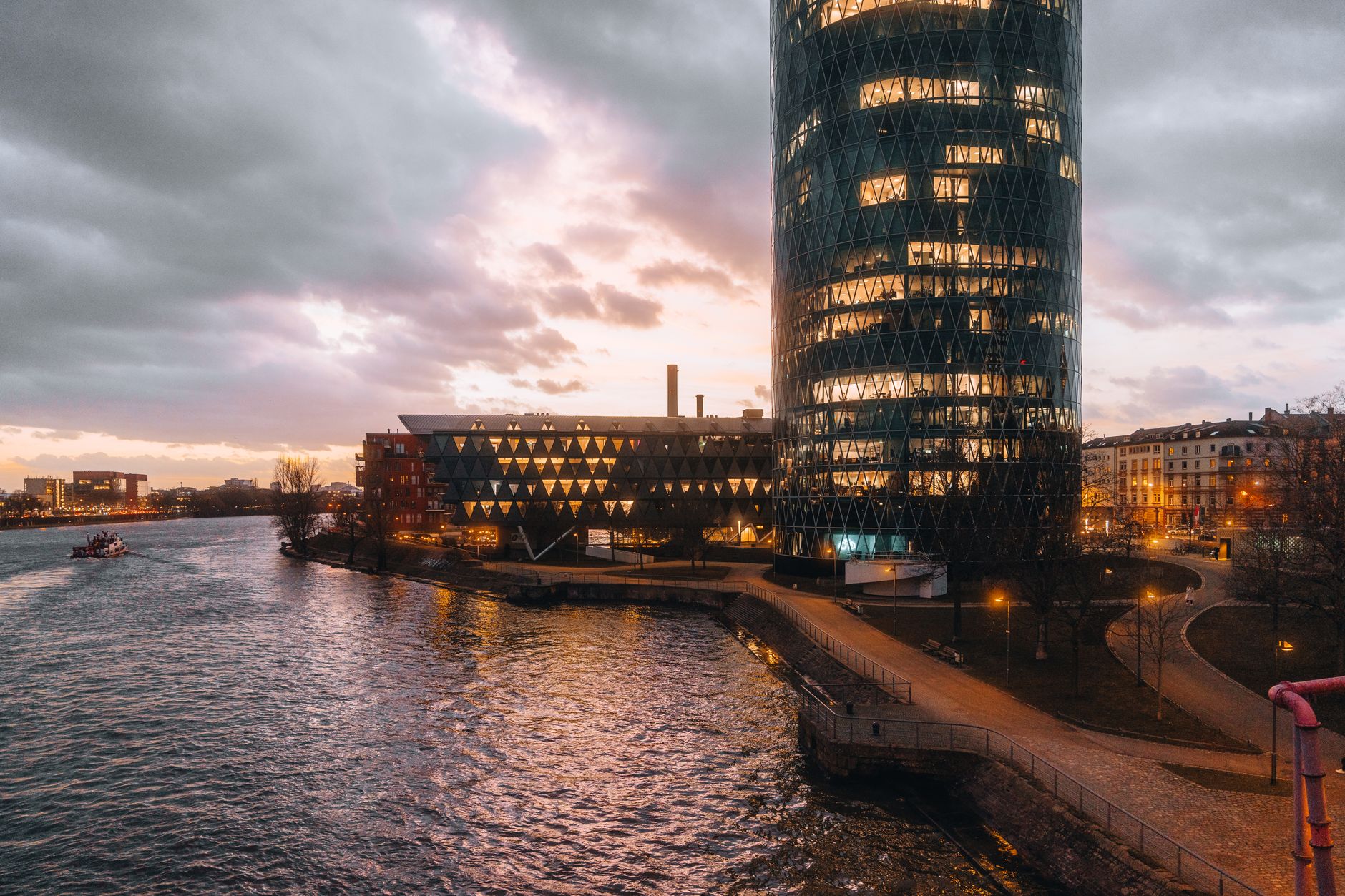 Scenic view of the illuminated Westhafen Tower and surrounding buildings at sunset in Frankfurt, Germany.