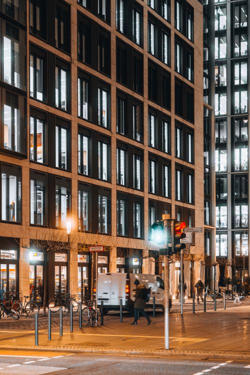 Free Urban night scene featuring modern office buildings and a city street intersection under bright lights. Stock Photo