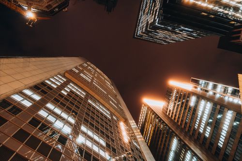 Free A dramatic view of illuminated skyscrapers reaching into the night sky in a bustling urban downtown. Stock Photo