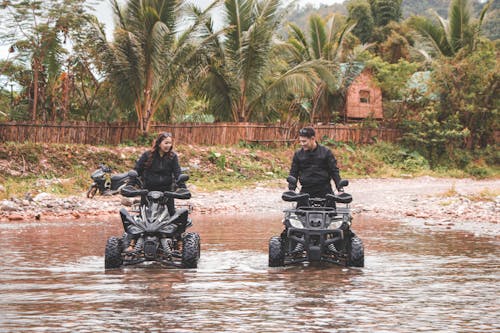 Two People Riding Quad Bikes in Water 