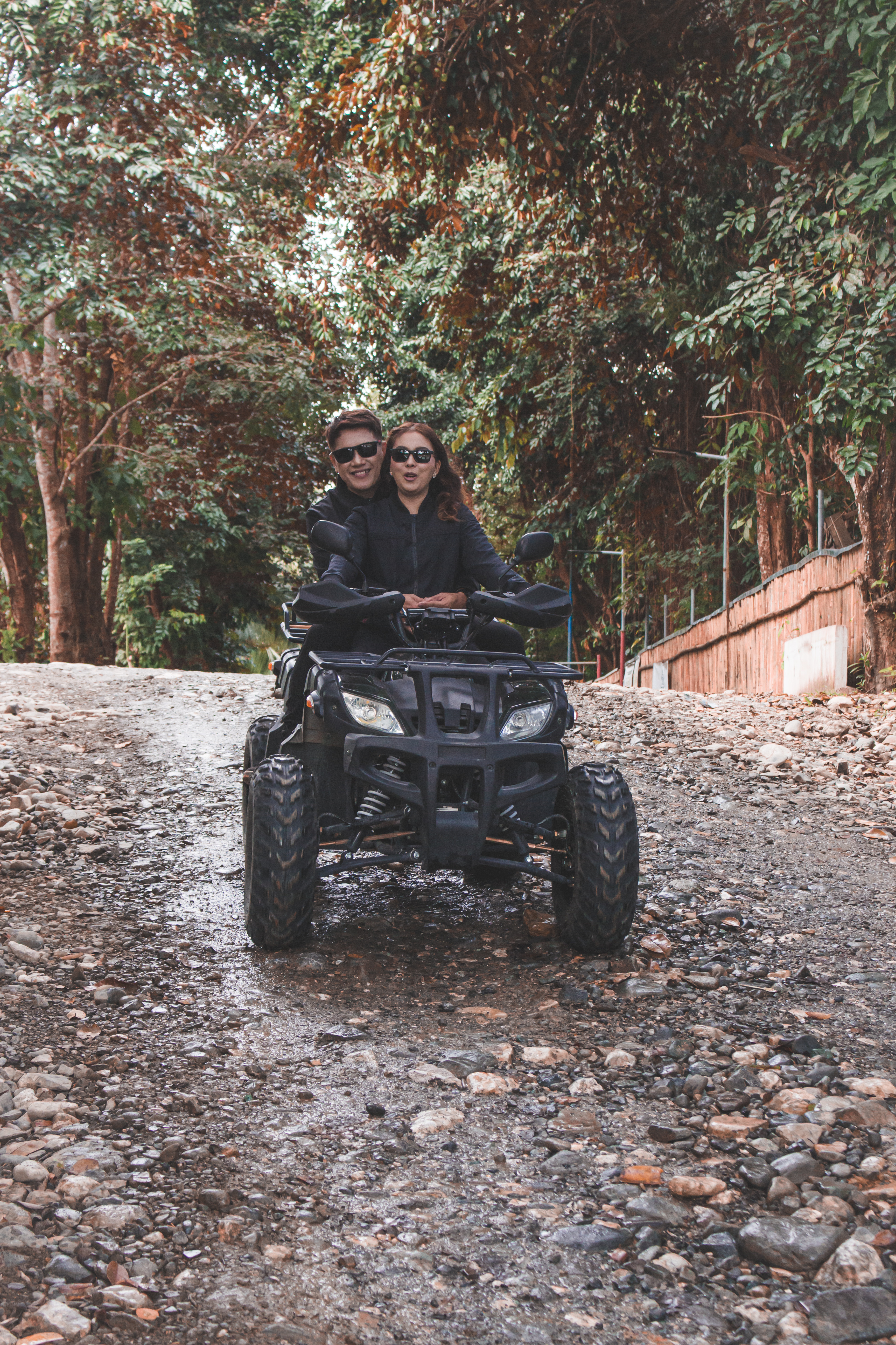 A couple enjoys a thrilling ATV ride through a rugged countryside path surrounded by lush greenery.