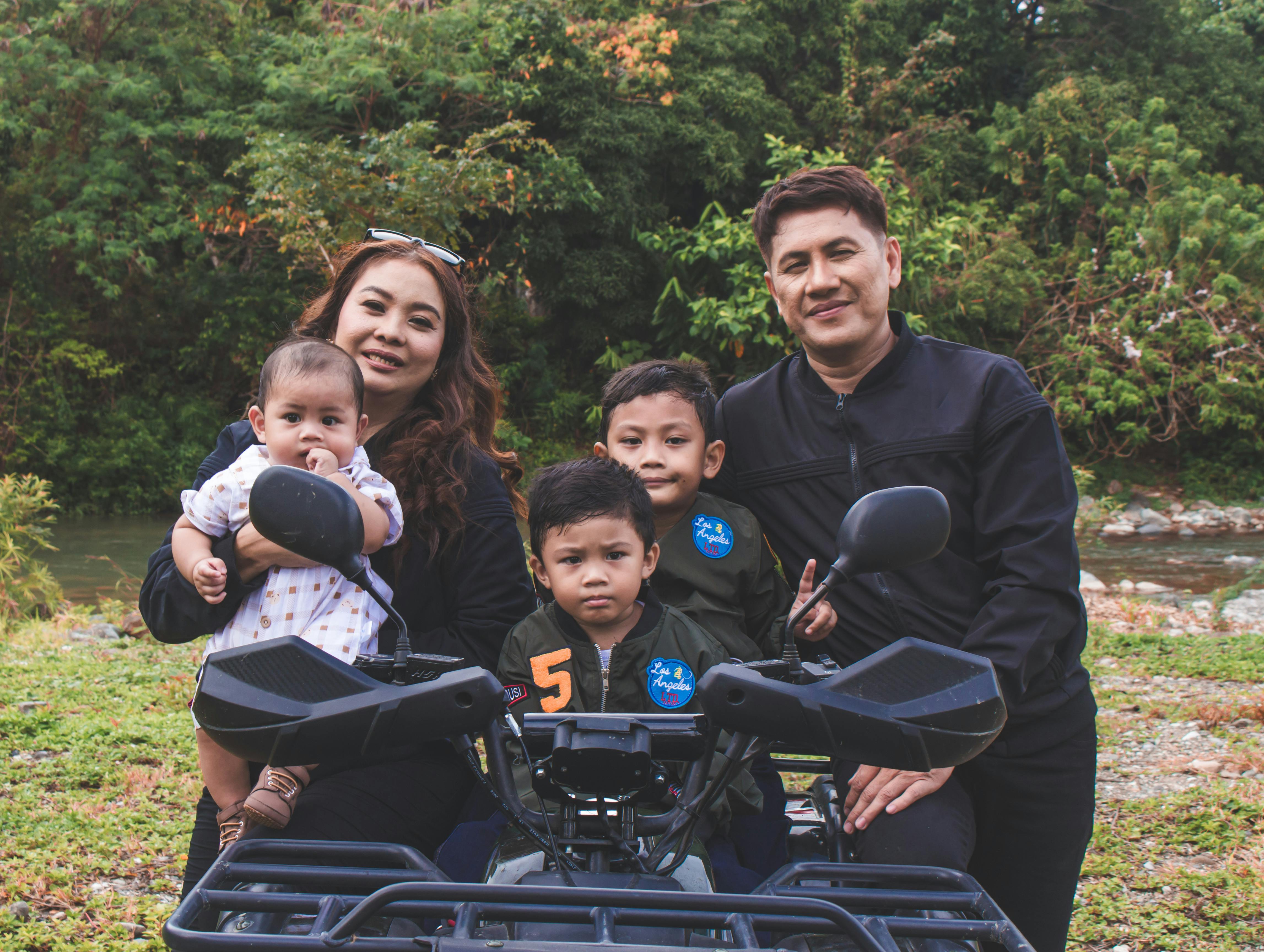 Happy family posing together outdoors with a quad bike