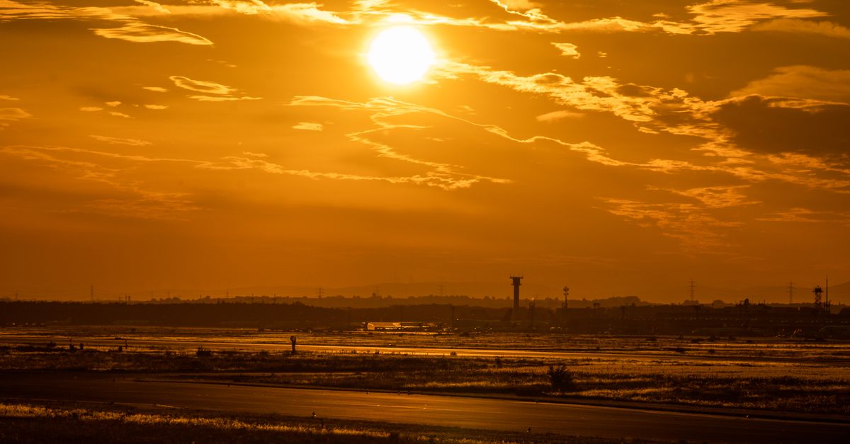 Stunning golden sunset over an airport runway, highlighting the sky's warm hues.