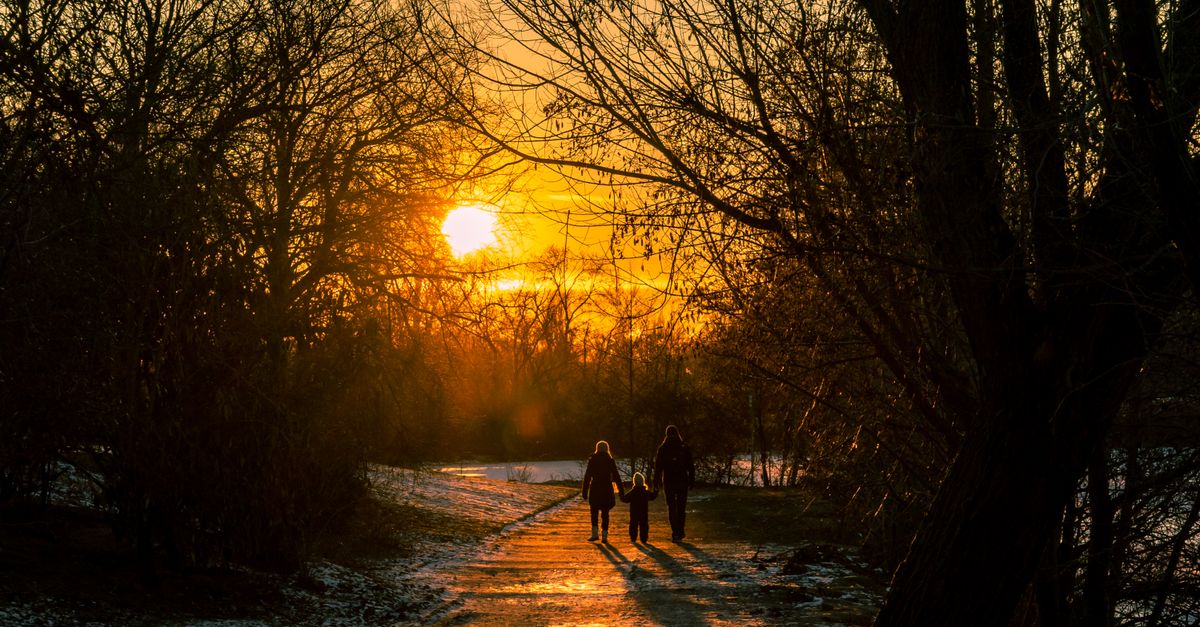 A peaceful sunset over a suburban Texas neighborhood, with a silhouette of a mother and child walking hand in hand