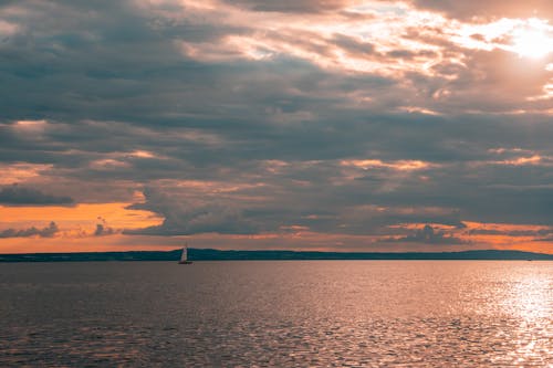 Cloud over Sea and Sailing Sailboat at Sunset