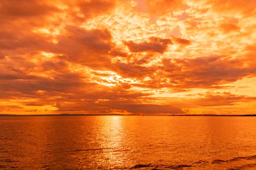 Breathtaking view of a vivid orange sky reflecting over a calm lake during sunset.
