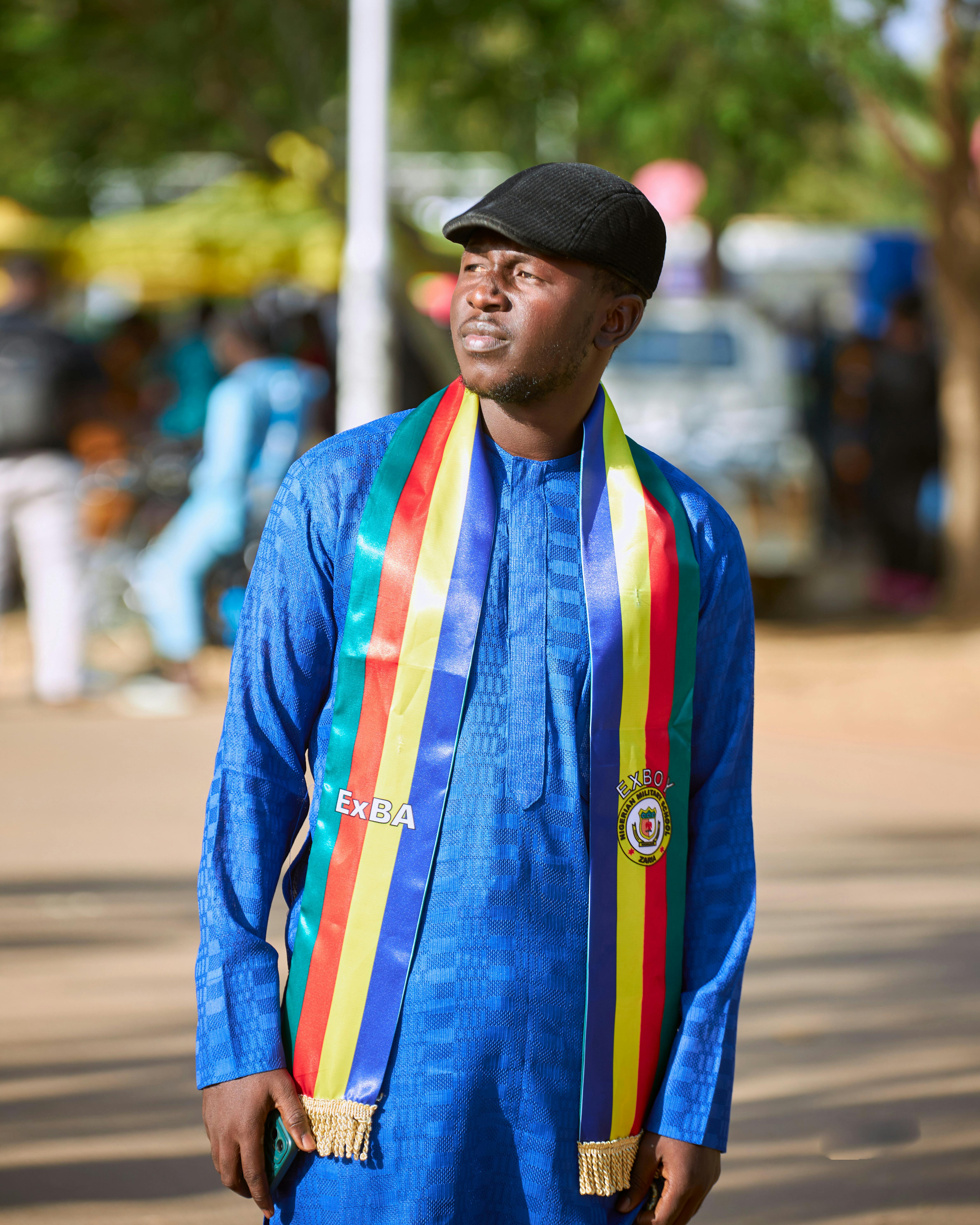 Portrait of a man in vibrant traditional clothing with a colorful striped scarf outdoors.