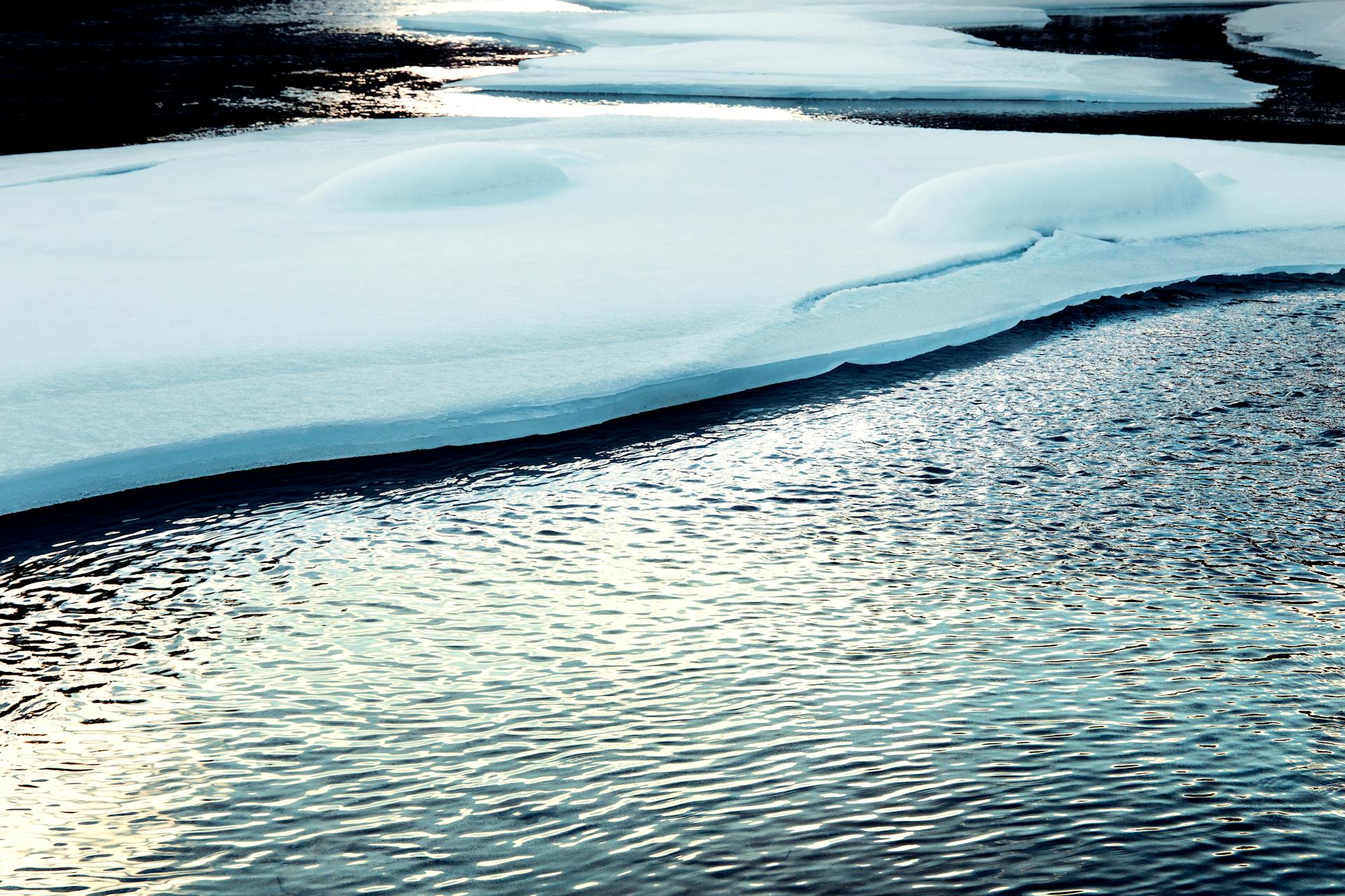 Calm winter lake with snowy ice formations reflecting the cold and serene atmosphere.