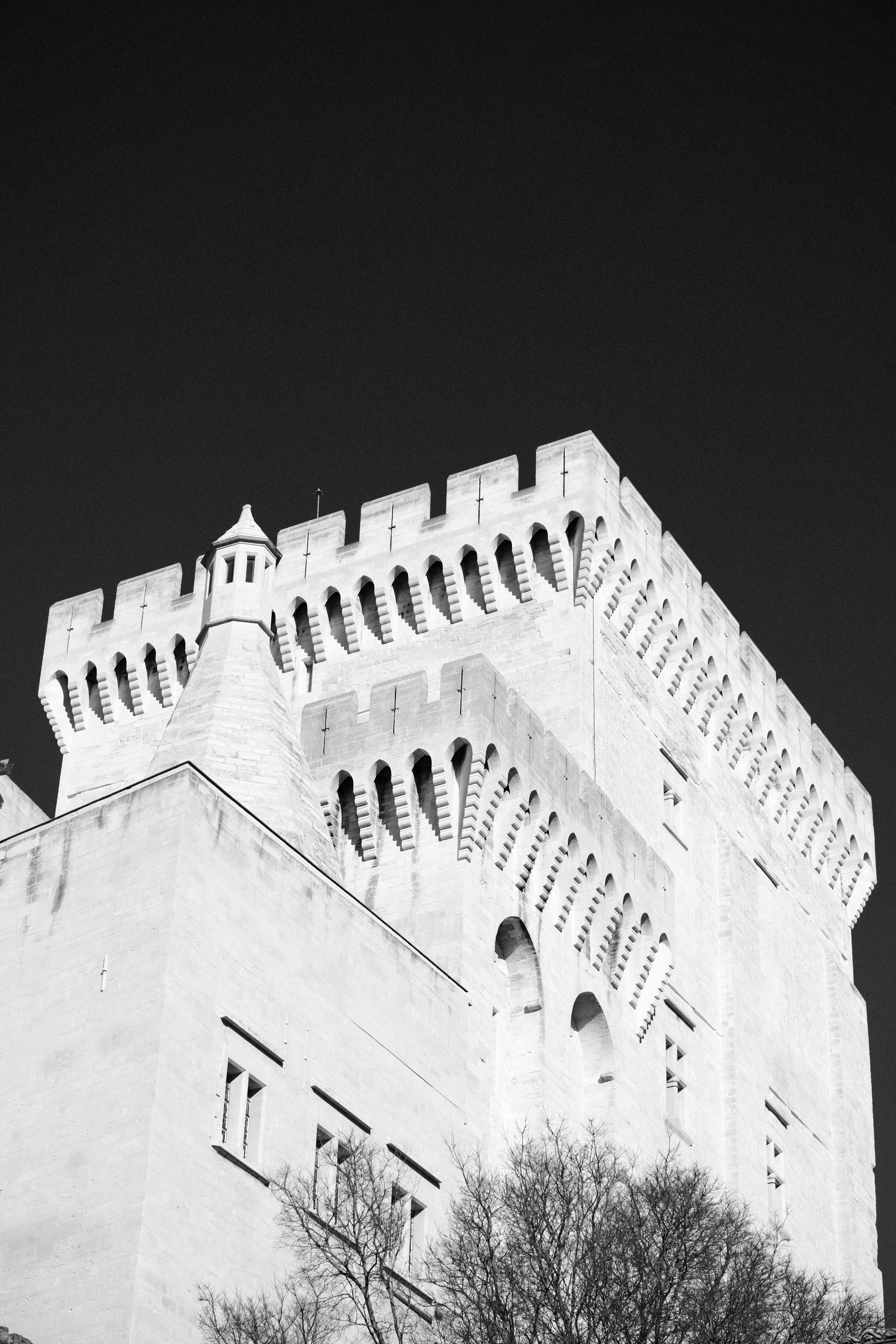 Dramatic low-angle view of a historical stone castle tower in monochrome.
