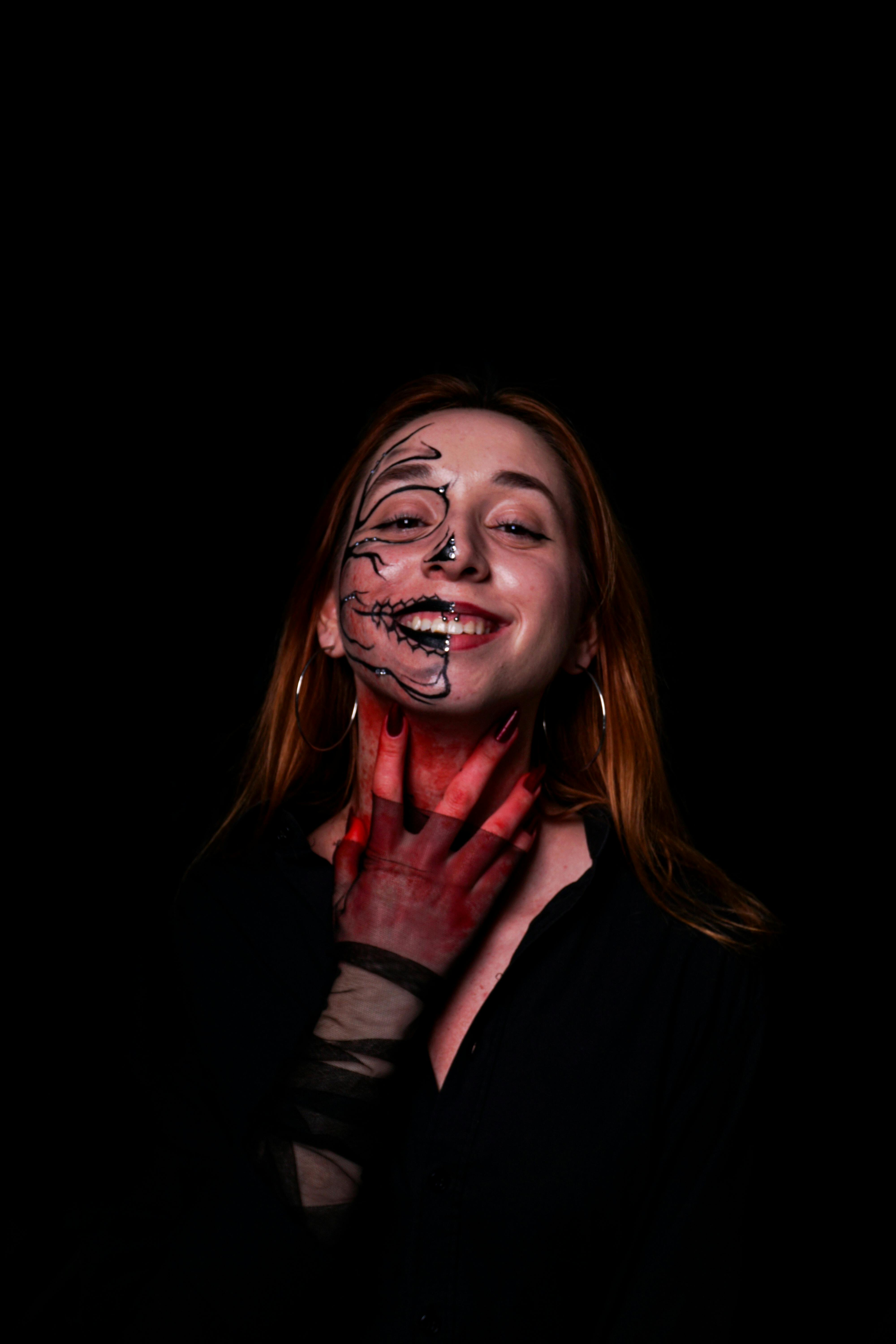 Free A captivating portrait of a smiling woman with Halloween skeleton makeup on a black background. Stock Photo