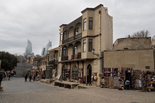 Street view of Baku's historic architecture with Flame Towers in the background.