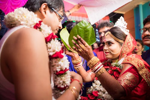 Woman in Traditional, Wedding Clothing Holding Leaves over Man in Ceremony